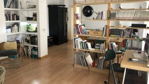 A well-organized living space with a wooden floor, a desk with a computer, and shelves filled with books and decorative items. - Monti Parioli House (Roma)