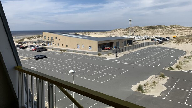 A view of a parking lot with a building in the foreground, a beach, and a clear sky. - F2 Apartment near beach with parking and pets allowed (Fort-Mahon-Plage)