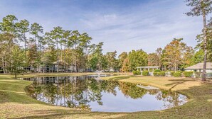 Un parcours de golf avec un étang, des arbres et un kiosque.
