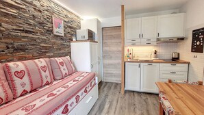 Une cuisine chaleureuse avec des meubles blancs, un plan de travail en bois et un mur en pierre.