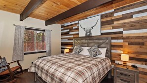 A bedroom with a wooden ceiling, a bed with plaid bedding, two bedside lamps, and a window with curtains. - Big Bear Escape By Destination Big Bear: Modern Cabin Elegance! Gameroom! Hot Tub! Fenced Yard! (Big Bear Lake)