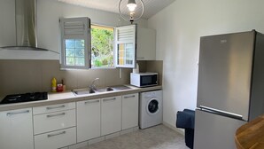 Une cuisine compacte équipée d’une cuisinière à gaz, d’un évier, d’un four à micro-ondes et d’un lave-linge.
