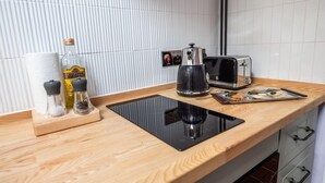 Una cocina con encimera de madera, cafetera, tostadora y una bandeja con pan.