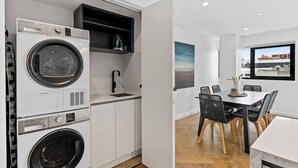 A compact kitchen with a washing machine, a sink, and a dining area with a table and chairs. - Sleek City Pad with a Garden Rooftop (Hobart)