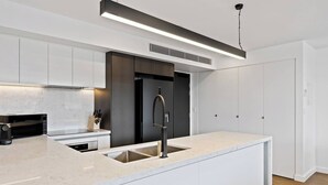 A modern kitchen with a central island, a built-in oven, and a sleek faucet. - Sleek City Pad with a Garden Rooftop (Hobart)