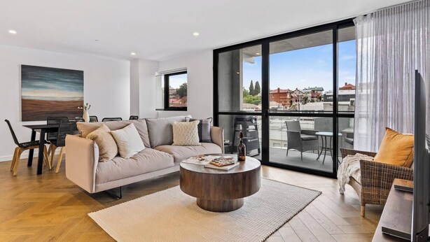 A modern living room with a sofa, coffee table, and dining area. - Sleek City Pad with a Garden Rooftop (Hobart)