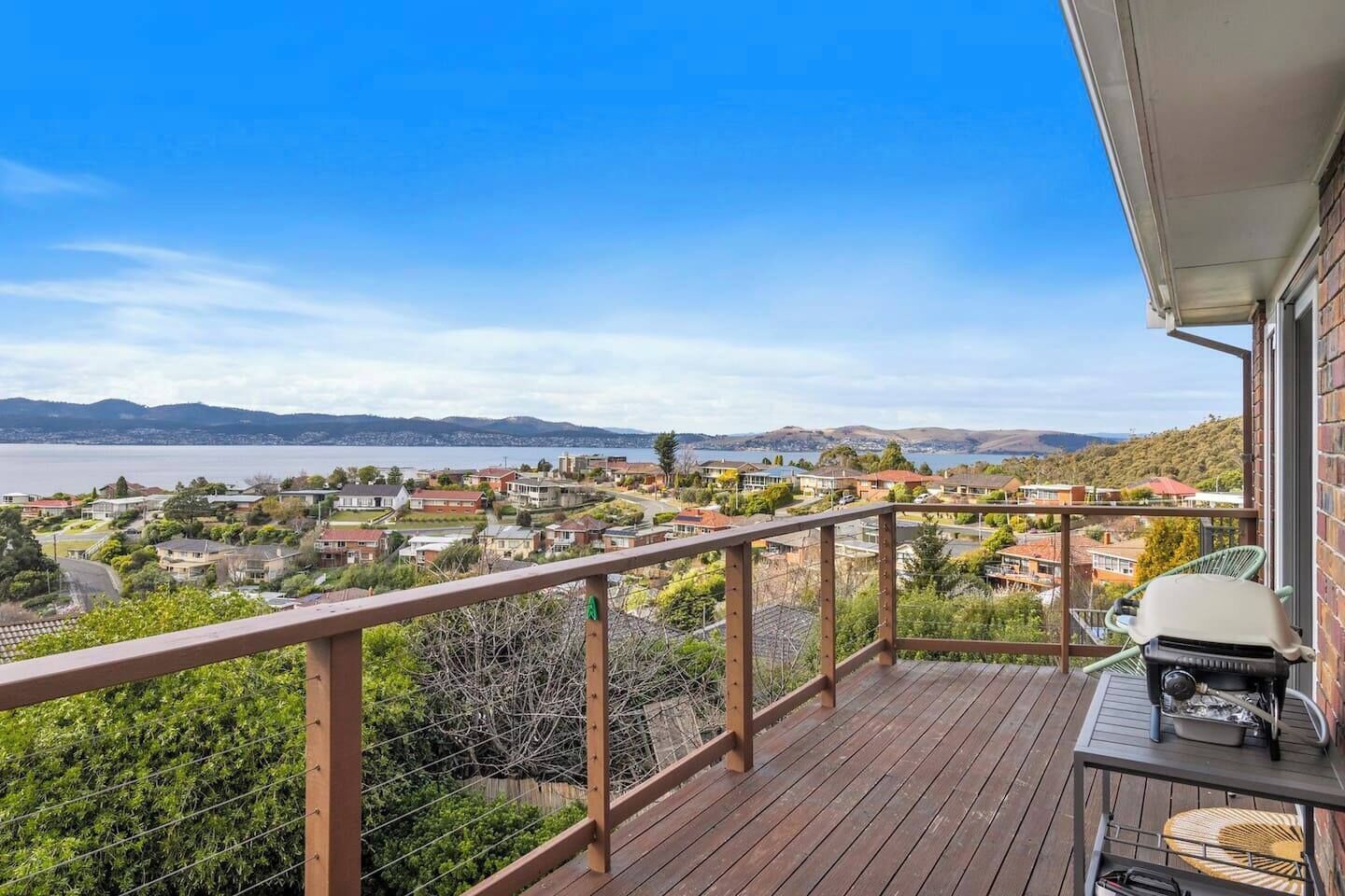 Eine Holzterrasse mit Blick auf eine Küstenstadt und Berge.