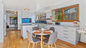Una cocina moderna con armarios blancos, una isla central con asientos y un ventanal con vistas a zonas verdes.