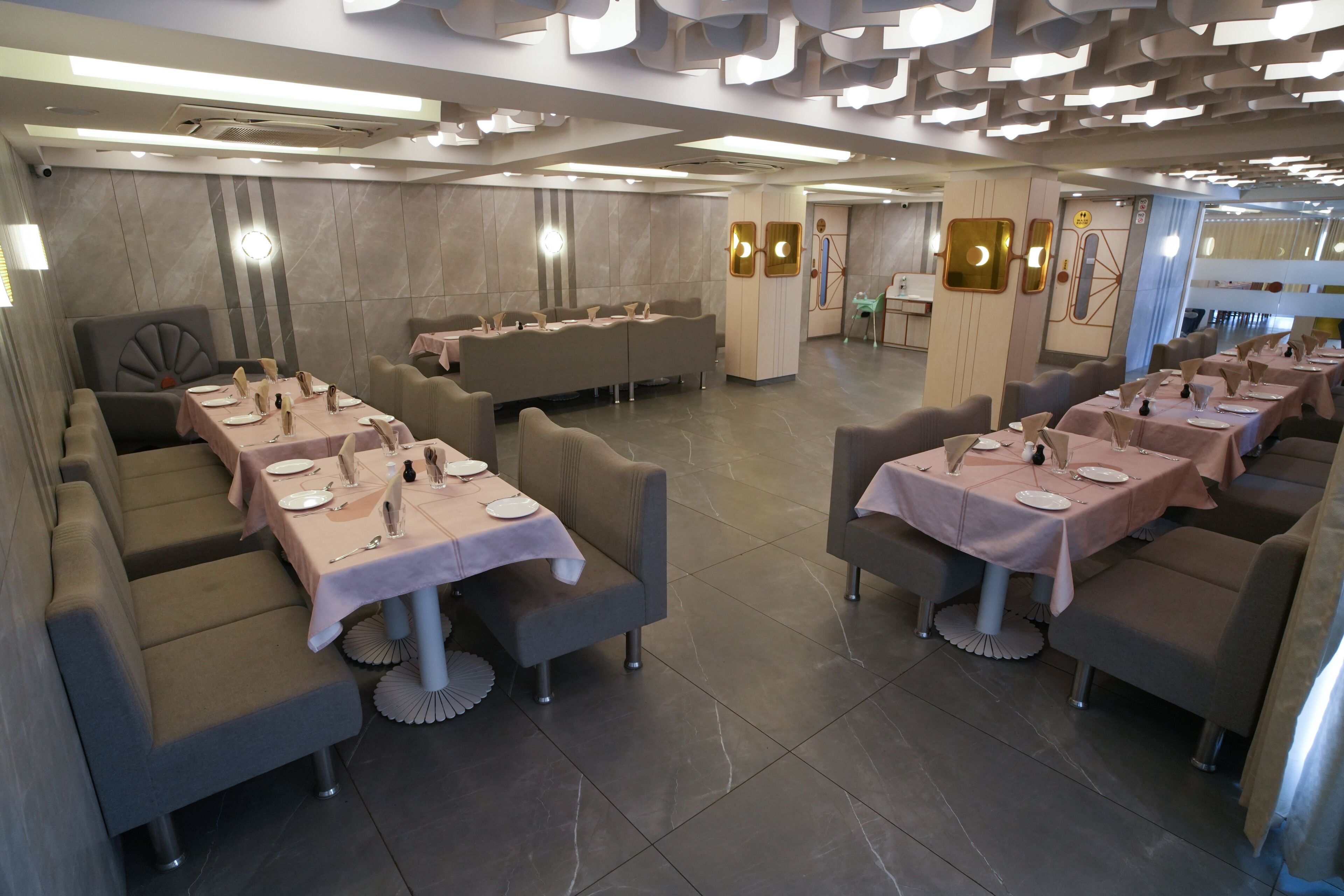 A modern restaurant with multiple dining areas, each with tables set for guests.