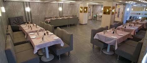 A modern restaurant with multiple dining areas, each with tables set for guests.