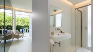 A modern bathroom with a large mirror, a white sink, and a glass shower enclosure. - Beautiful modern villa with private pool, just steps from the sea in Fanusa, Syracuse. (Siracusa)