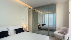 A modern hotel room with a large bed, a seating area, and a mirrored closet. - Beautiful modern villa with private pool, just steps from the sea in Fanusa, Syracuse. (Siracusa)
