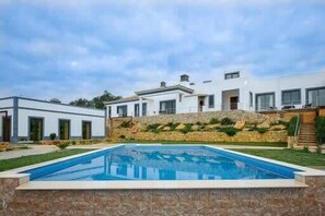 Een modern huis met een zwembad, stenen muren en een verzorgde tuin.