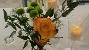 Une table ornée d’un vase de fleurs, de deux bougies et d’un photophore en verre.