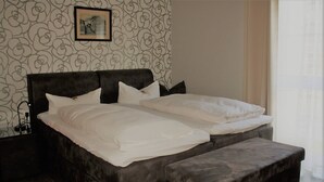 Un lit double avec une tête de lit, deux oreillers et une table de chevet avec une lampe.