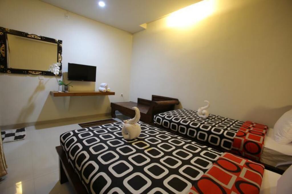 A hotel room with two beds, a TV, a small table, and a mirror.