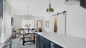 A modern kitchen with a large island, dark cabinetry, and a checkered floor.