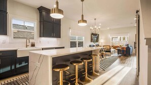 A modern kitchen with dark cabinets, a marble island, and bar stools.