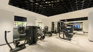 Een moderne sportschool met diverse trainingsapparaten, een grote spiegel en een schoon, minimalistisch design.