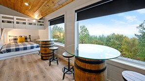 A bedroom with a bed, a glass table, and wooden barrels.