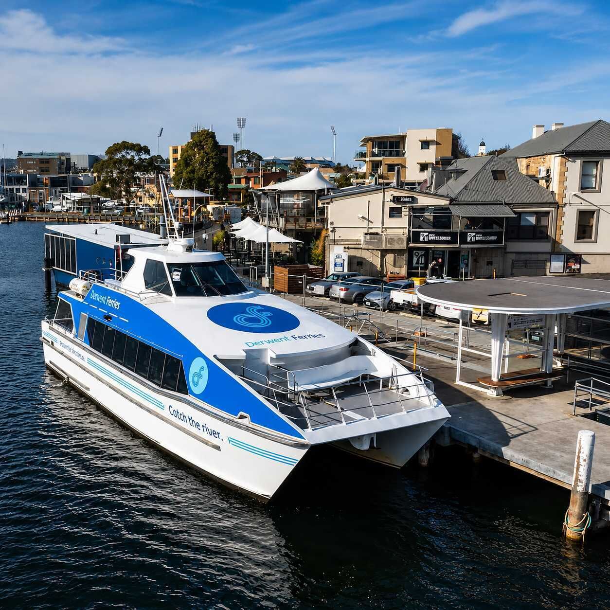 A ferry docked at a pier with a cityscape in the background.