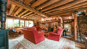 A rustic wooden interior with a fireplace, red upholstered furniture, and patterned rugs. - Hell Fyre 1594 by inspirestays.com - a cottage that sleeps 2 guests in 1 bedroom (Itchingfield, nr Horsham)