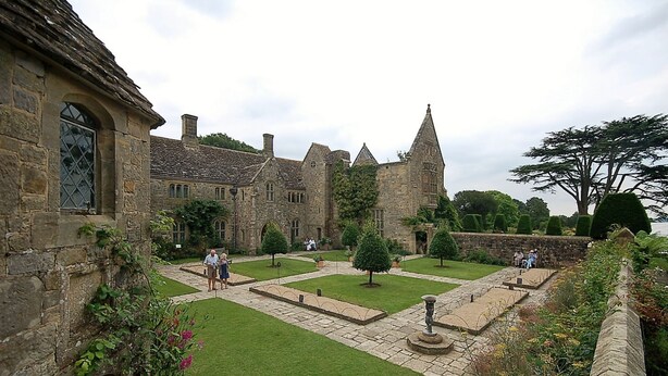 A historic stone building with a courtyard, featuring a central lawn, stone pathways, and a statue. - Hell Fyre 1594 by inspirestays.com - a cottage that sleeps 2 guests in 1 bedroom (Itchingfield, nr Horsham)