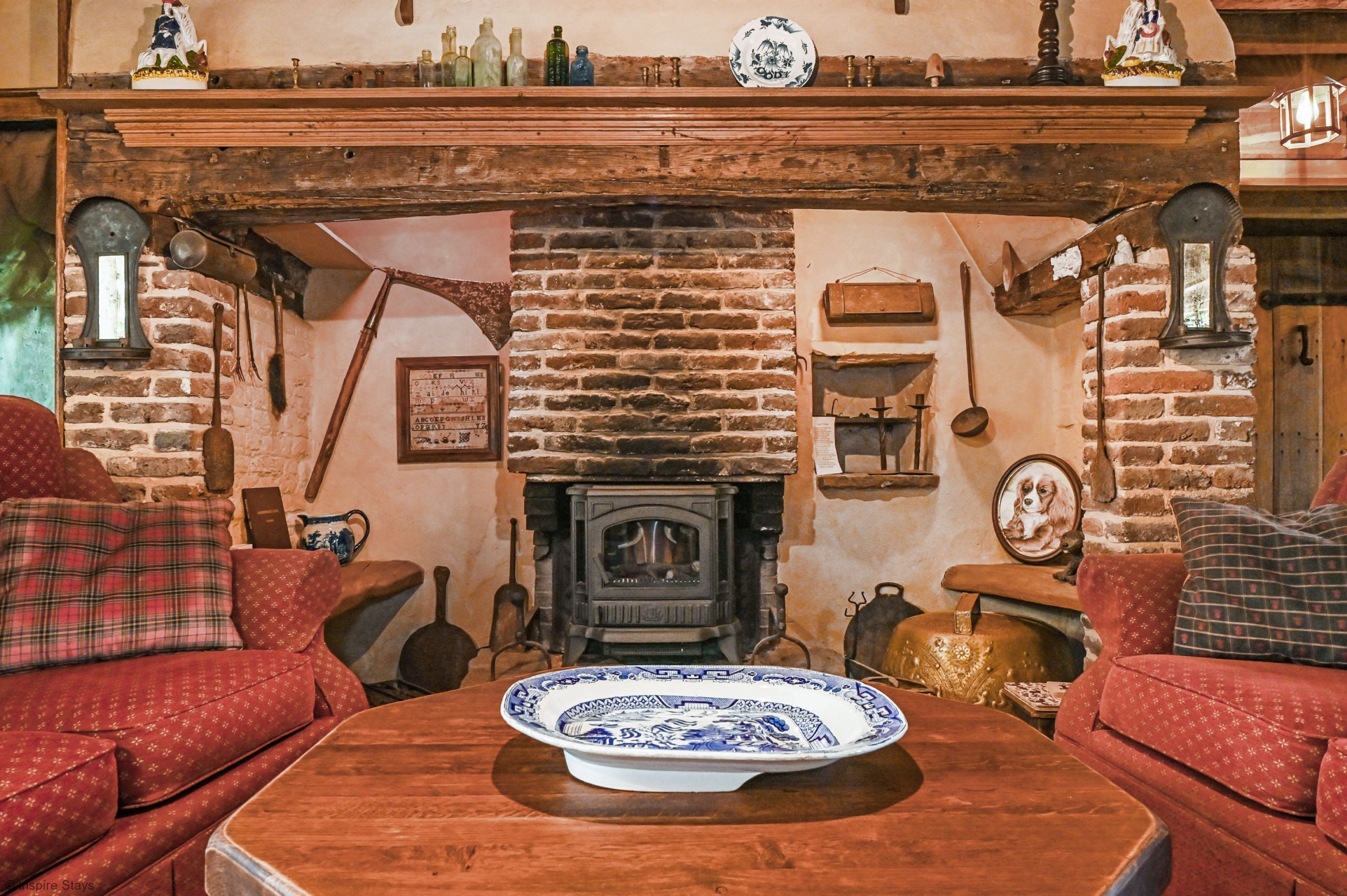 A traditional room with a brick fireplace, wooden furniture, and a variety of decorative items.