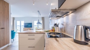 A modern kitchen with wooden cabinets, a built-in stove, and a kettle. - Wiking-Koje 3 - Elevator, 1st Floor, Underfloor Heating, Shower, Washing Machine (Schleswig)