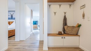 A hallway with a wooden floor, a bed, a TV in the background, and a wall with decorative skulls and a basket. - Wiking-Koje 5 - Elevator, 1st Floor, Shower, TV, Wi-Fi, Garden Furniture,Parking (Schleswig)