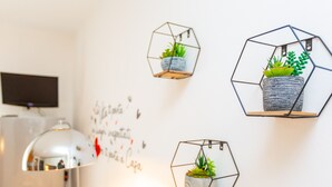 A wall with three hexagonal planters containing plants, a white wall with some text, and a white ceiling light fixture. - HAPPY HOUSE [7 minutes from MXP and 30 minutes from Milan] (Busto Arsizio)