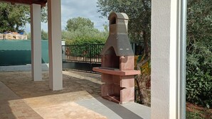 A stone-built outdoor oven, a covered patio area, and a view of a residential building in the background. - Studio Nena (Rovinj)
