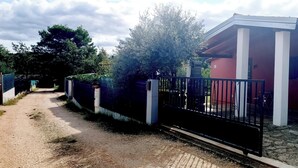 A gated driveway leading to a building with a red exterior and white columns. - Studio Nena (Rovinj)