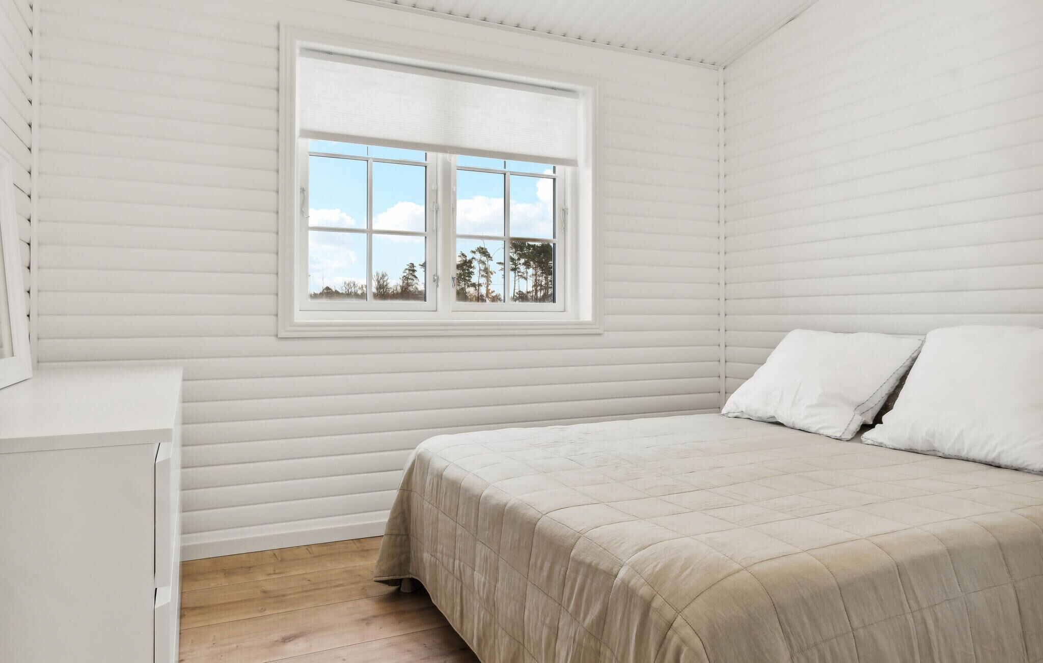 A bedroom with a bed, a window, and a white dresser.