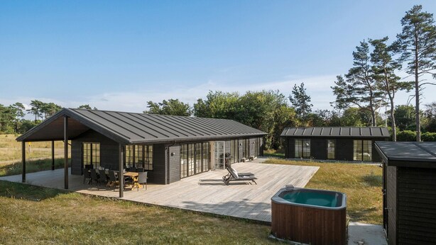 Un espace extérieur moderne, aménagé en patio, avec un jacuzzi, une terrasse en bois et un coin salon couvert équipé de tables et de chaises.