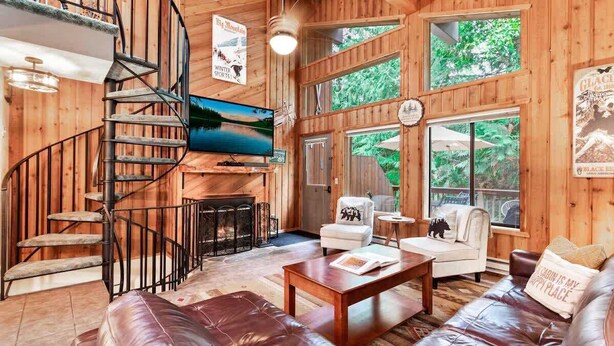 A wooden interior with a spiral staircase, a television, a fireplace, and a sofa.
