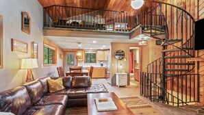 A spacious living area with a leather sofa, a wooden coffee table, and a spiral staircase.