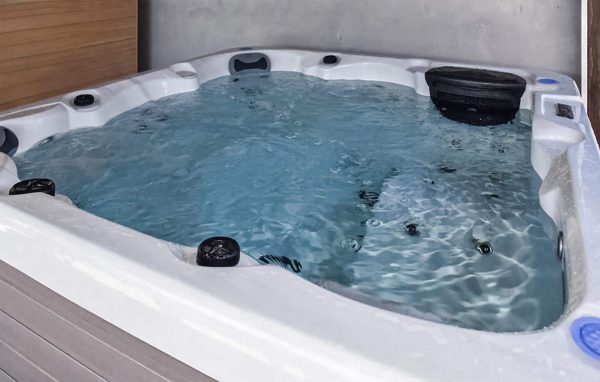 Una vasca idromassaggio con acqua, un coperchio nero e un pannello di controllo.