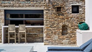 A stone exterior with a modern bar area, two lounge chairs, and a decorative shell.