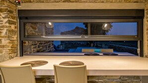 A dining area with a stone wall, a large window, and a table with chairs.