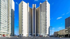Um edifício moderno de grande altura com um átrio central, rodeado por espaços de estacionamento e outros edifícios.