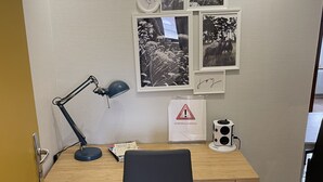 Een werkplek met een bureau, stoel, lamp en wanddecoratie.