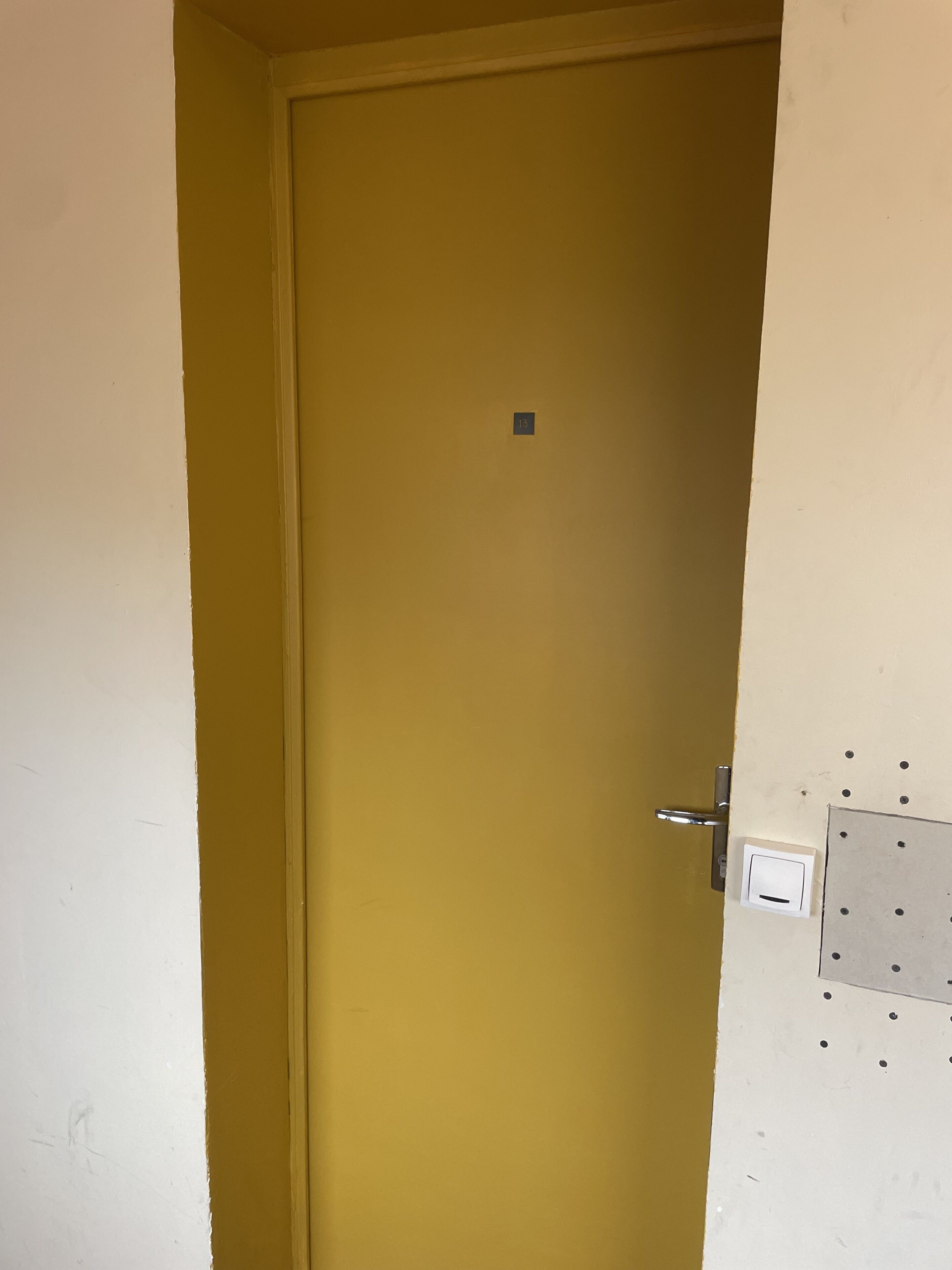 Une porte fermée avec une petite plaque carrée fixée au mur.