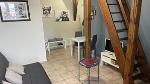 Een woonkamer met een bank, een bijzettafeltje, een televisie en een ladder.