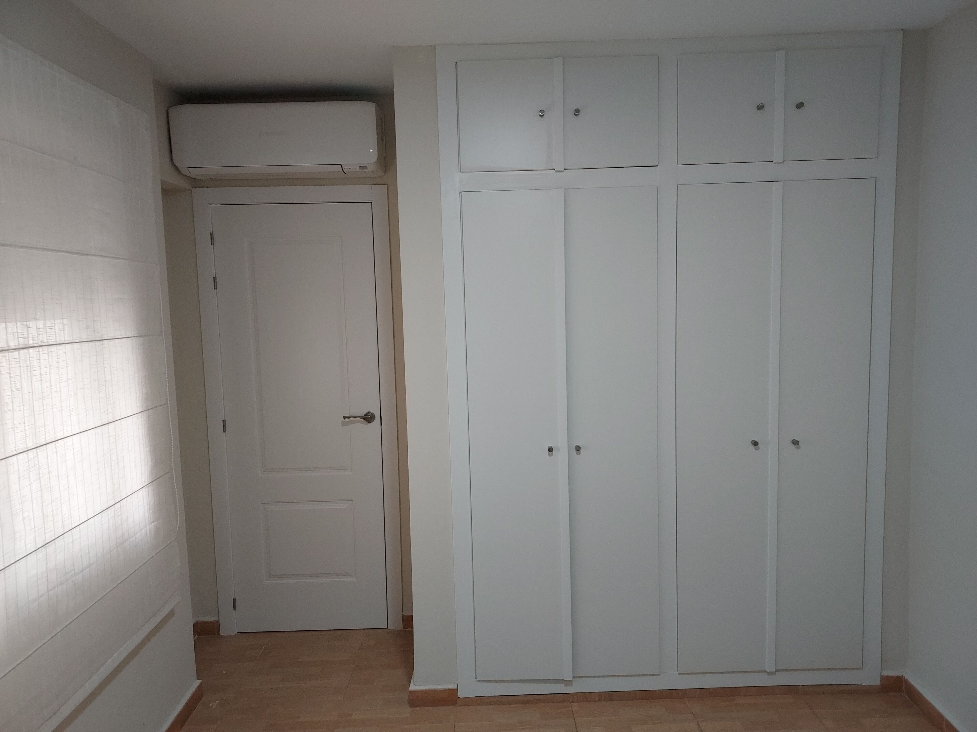 Ein Flur mit einer weißen Tür und einem weißen Schrank mit mehreren Türen.