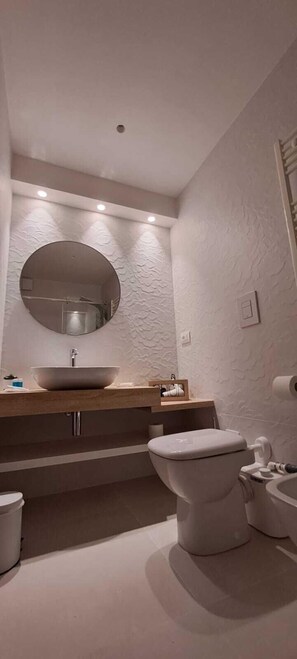 A modern bathroom with a round mirror, a vessel sink, and a toilet. - B&B Tramonto Sul Mare (Termoli)