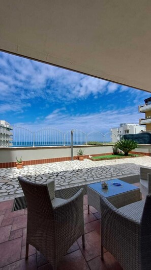 An outdoor patio with wicker furniture and a view of the sea. - B&B Tramonto Sul Mare (Termoli)