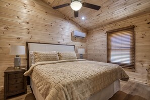 A wooden cabin bedroom with a bed, nightstands, a ceiling fan, and a window with blinds.