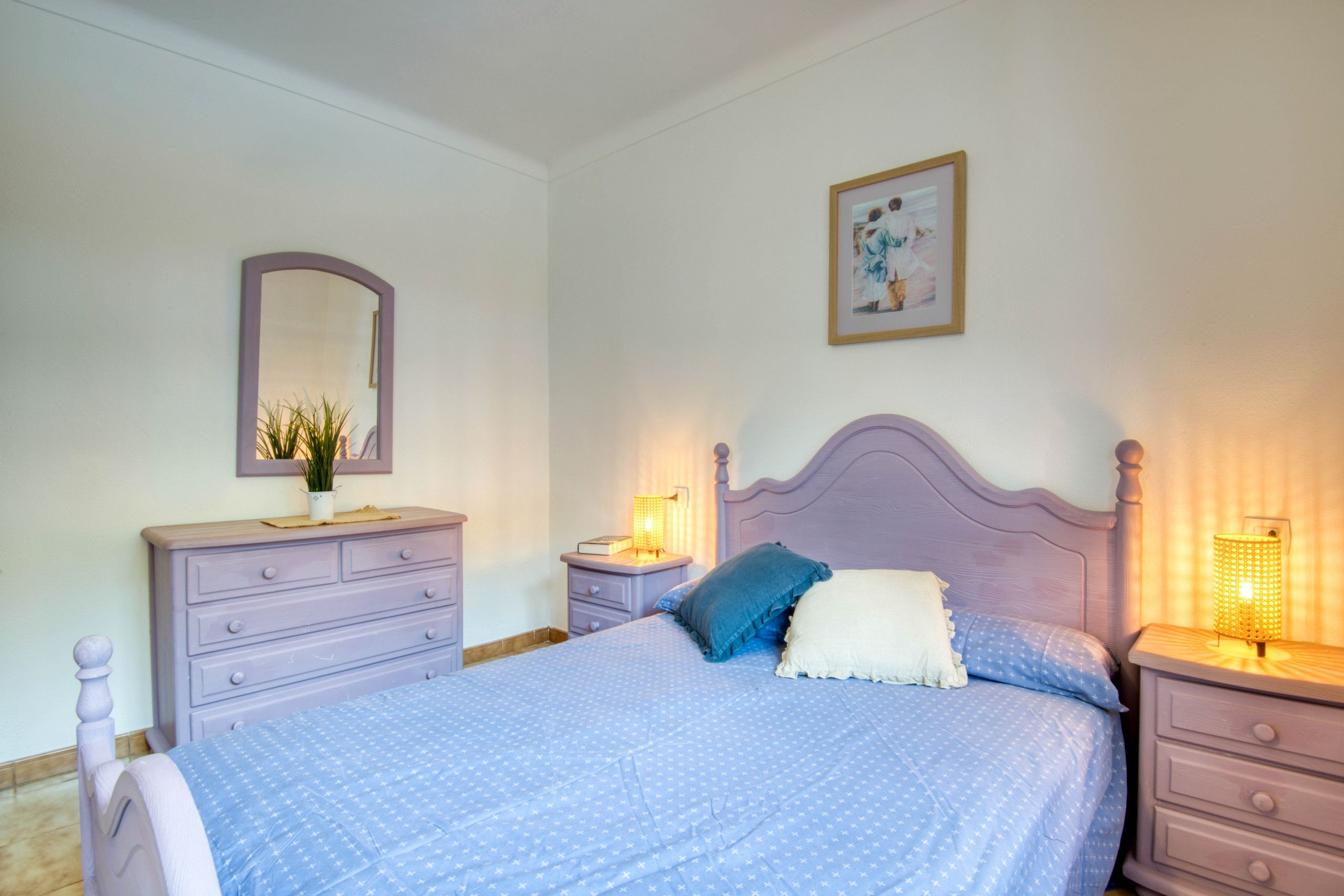 Een slaapkamer met een bed, een kaptafel, nachtkastjes en een spiegel.