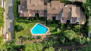 An aerial view of a residential area with multiple houses, a swimming pool, and a road with parked cars. - TREBOL: Apartment in l'Escala with community pool and garden, ideal for families (L'Escala)